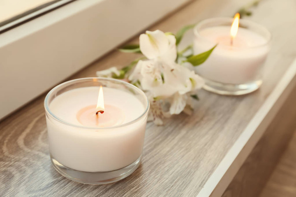 Burning wax candles with flowers on windowsill - Photo, Image
