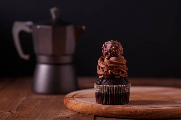 Tasty chocolate cupcakes on wooden board. Dark background. Geyser coffee - Foto, Imagen