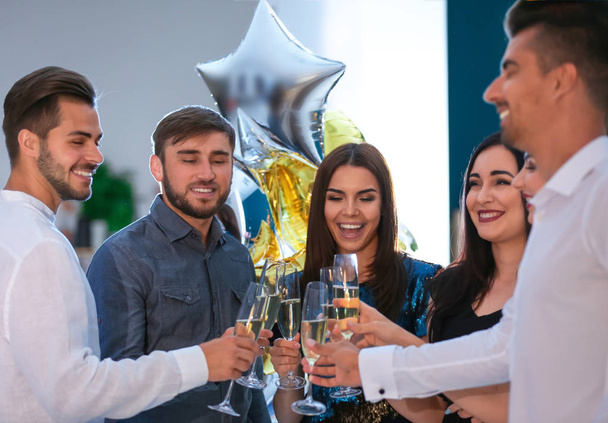 Молоді люди смердять келихи з шампанським на вечірці на день народження в клубі
 - Фото, зображення