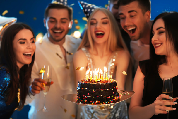 Mujer joven con sabroso pastel y sus amigos en la fiesta de cumpleaños en el club
 - Foto, imagen