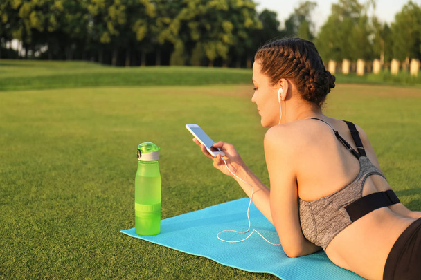 Güzel genç kadın yoga mat açık havada yalan sırasında müzik - Fotoğraf, Görsel