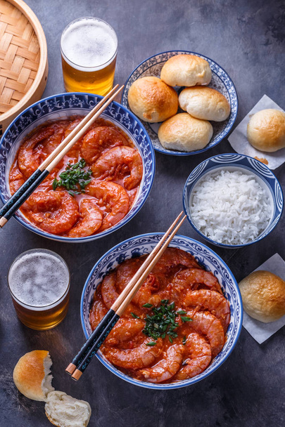 Camarones asiáticos picantes en salsa de tomate con arroz, bollos y cerveza, vista superior
 - Foto, imagen