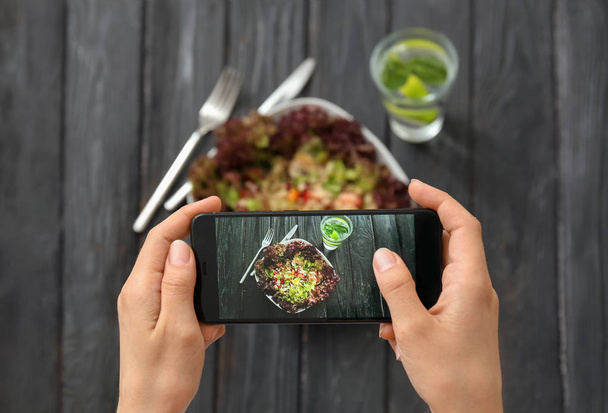 Woman taking photo of tasty quinoa salad with mobile phone - Фото, зображення
