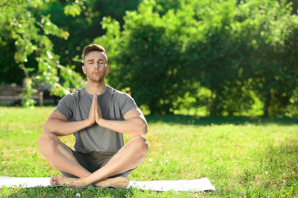Sporty man practicing yoga in park - Foto, imagen