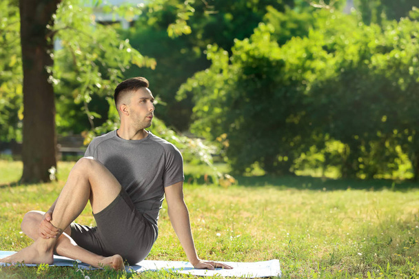 Sporty man practicing yoga in park - Photo, Image