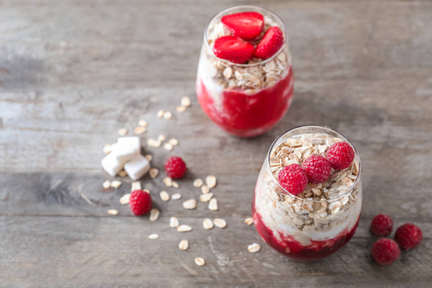 Delicious oatmeal desserts with fresh raspberries in glasses on wooden table - Фото, изображение