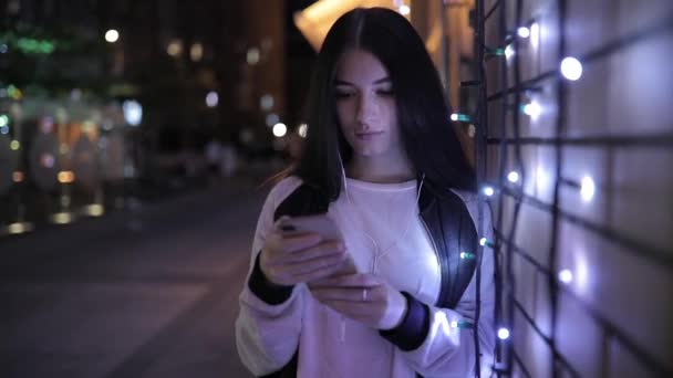 Mujer usando smartphone navegando por internet móvil en la ciudad nocturna del centro
 - Metraje, vídeo