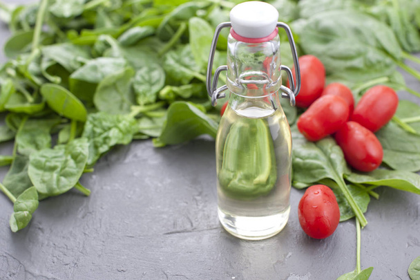 Many Fresh spinach leaves, vegetable oil in a bottle and small cherry tomatoes. Vitamins and health. Free space for text. Copy space. - Фото, изображение