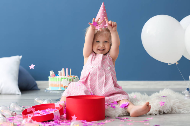 Söpö pieni tyttö syntymäpäiväjuhlissa korkki leikkii paperikonfetti sisätiloissa
 - Valokuva, kuva