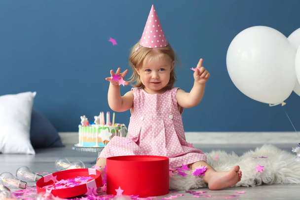 Linda niña en la tapa de fiesta de cumpleaños jugando con confeti de papel en el interior
 - Foto, imagen