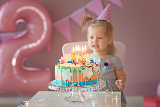 Menina bonito com bolo de aniversário sentado na cadeira no quarto
 - Foto, Imagem