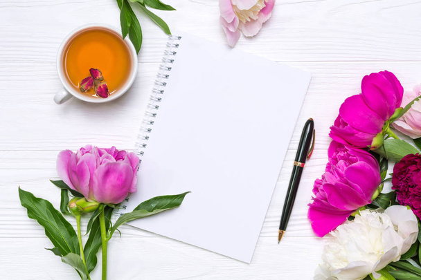 Cuaderno vacío con lugar para texto, pluma, una taza de té y flores de peonías
 - Foto, imagen