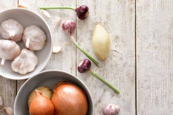 Different fresh garlic and onions on wooden table - Valokuva, kuva