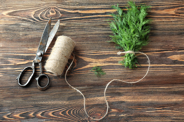 Svazek čerstvého kopru s nůžkami a vlákno na dřevěné pozadí - Fotografie, Obrázek