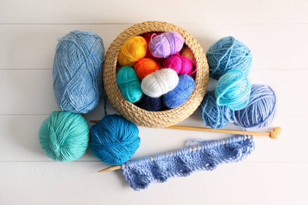 Wicker basket with different knitting yarn on table - Fotoğraf, Görsel