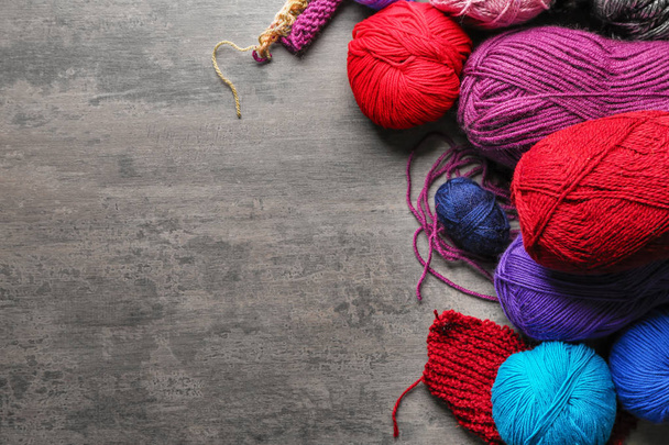 Colorful knitting yarn with unfinished clothes on table - Valokuva, kuva
