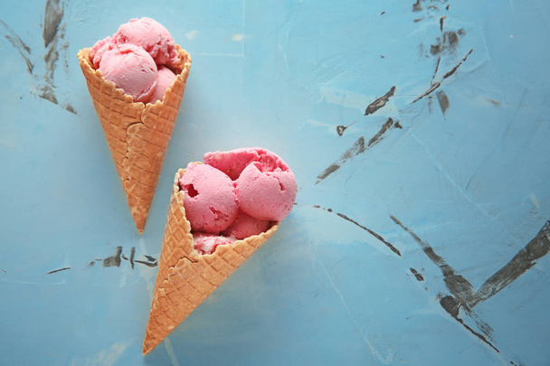 Conos de gofre con delicioso helado de fresa sobre fondo claro
 - Foto, Imagen