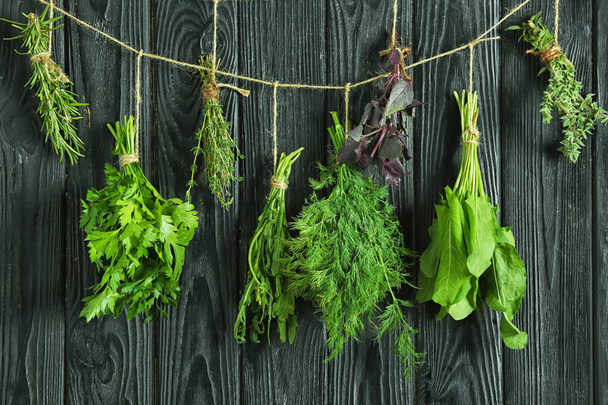 Fresh herbs hanging on string against wooden background - Foto, Imagem