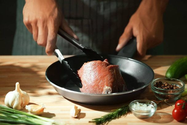 Homme préparant une délicieuse viande avec des épices dans la cuisine
 - Photo, image