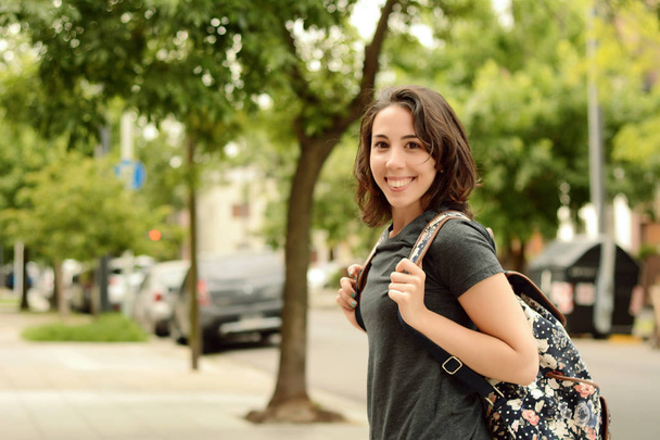 Portrait of young smiling woman walking in street with backpack. Outdoors - Foto, imagen