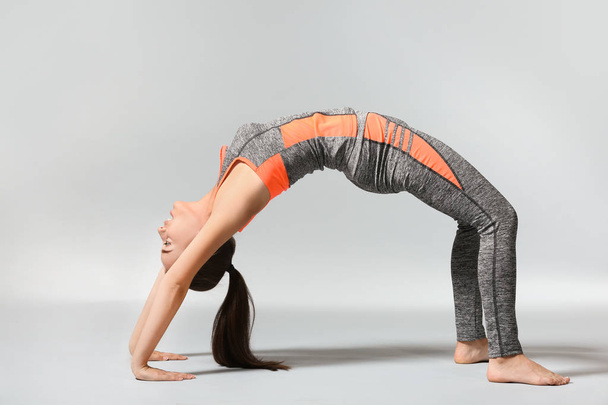 Jeune femme pratiquant le yoga sur fond gris
 - Photo, image