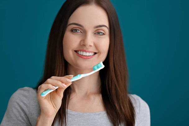 Young woman brushing her teeth on color background - Photo, image