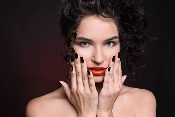 Fashionable young woman with black manicure on dark background - Photo, Image