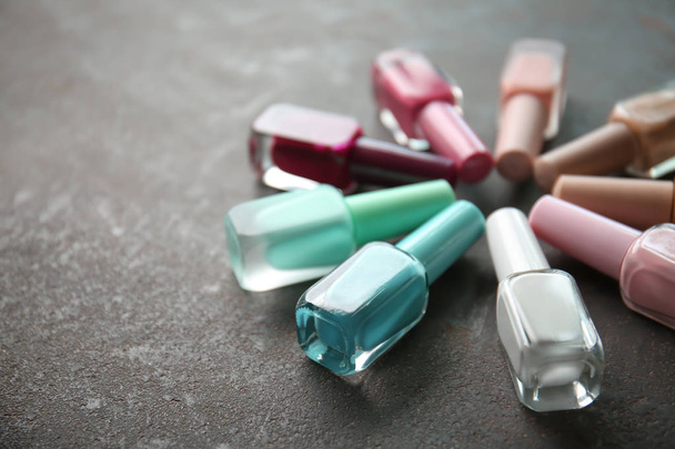 Flessen van kleurrijke nagel schoensmeer op grijze achtergrond - Foto, afbeelding