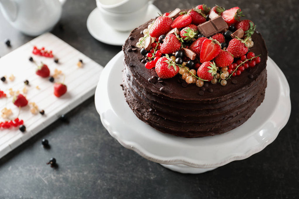 Вкусный шоколадный торт с клубникой и смородиной на тёмном столе
 - Фото, изображение