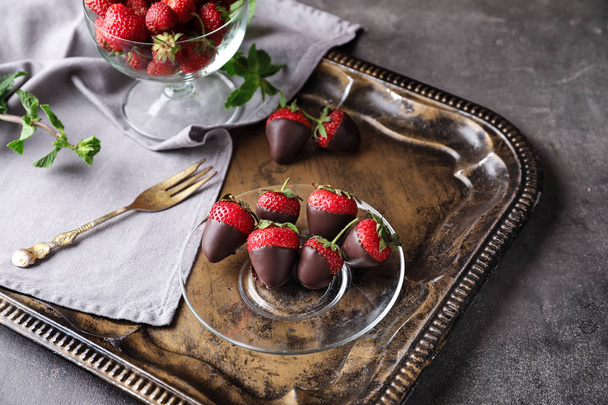 グレーのテーブルに美味しいチョコレートに浸したイチゴ付きのトレイ - 写真・画像