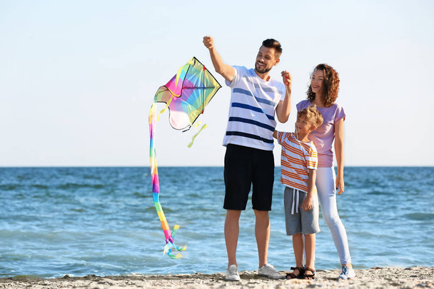 glückliche Familie fliegt Drachen in der Nähe des Meeres - Foto, Bild