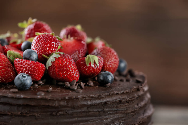 Tasty chocolate cake decorated with strawberry and blueberry, closeup - Photo, Image
