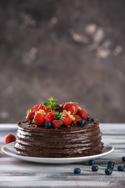 Tasty chocolate cake decorated with berries on wooden table - Fotoğraf, Görsel