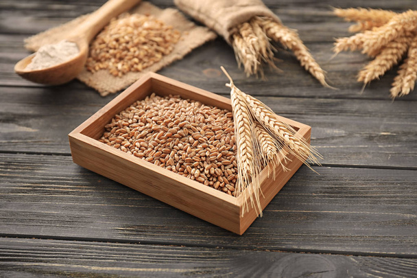 Wooden box with wheat grains and spikelets on table - Photo, Image