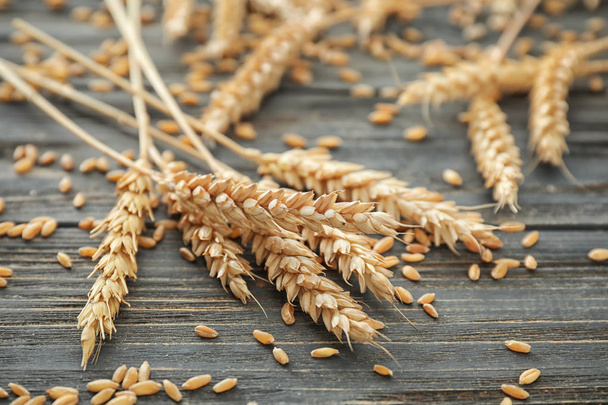 Wheat grains with spikelets on wooden background - Foto, afbeelding