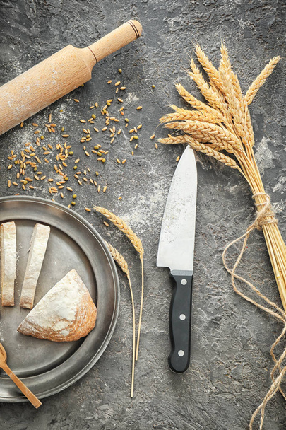 Komposition mit Brotscheiben und Weizenstacheln auf grauem Hintergrund - Foto, Bild