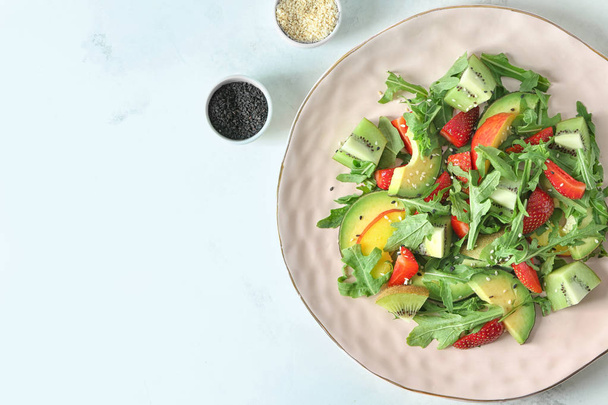 Тарелка с вкусным свежим салатом на светлом фоне
 - Фото, изображение