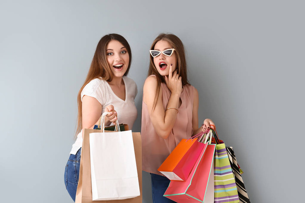 Beautiful young women with shopping bags on light background - Photo, image