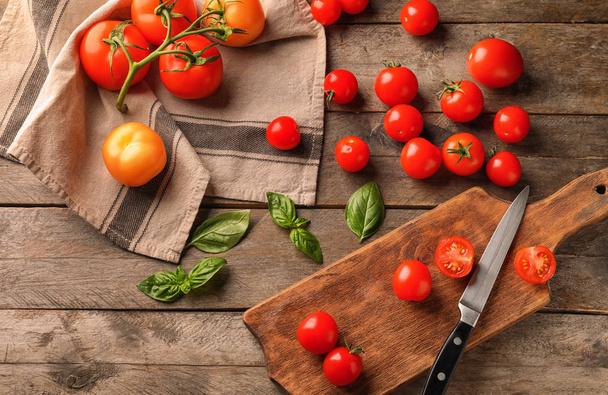 Cutting board with ripe cherry tomatoes on wooden background - Fotó, kép