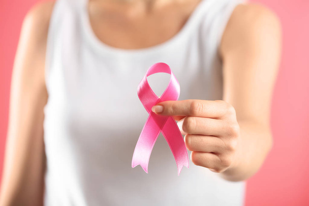 Beautiful woman holding pink ribbon on color background, closeup. Breast cancer concept - Fotoğraf, Görsel