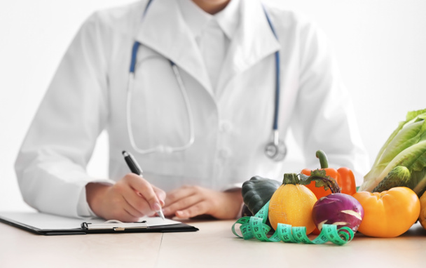 Ženské výživu sedí u stolu s schránky a zdravé produkty na bílém pozadí - Fotografie, Obrázek