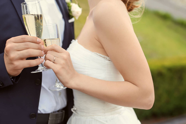 Счастливая свадебная пара с бокалами шампанского на открытом воздухе
 - Фото, изображение