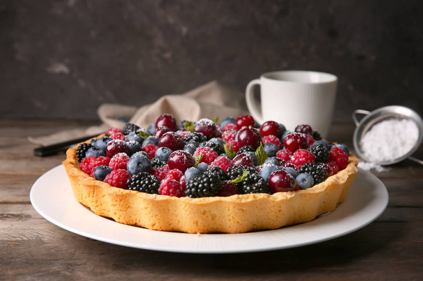 Тарелка с вкусным ягодным пирогом на деревянном столе
 - Фото, изображение