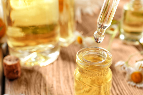 Chamomile essential oil dripping from pipette into bottle, closeup - Foto, Bild