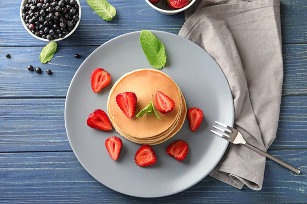 Plate with tasty homemade pancakes and strawberries on wooden table - Photo, Image