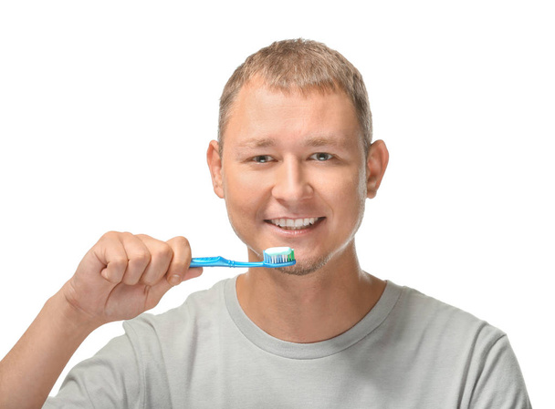 Man brushing his teeth on white background - Valokuva, kuva