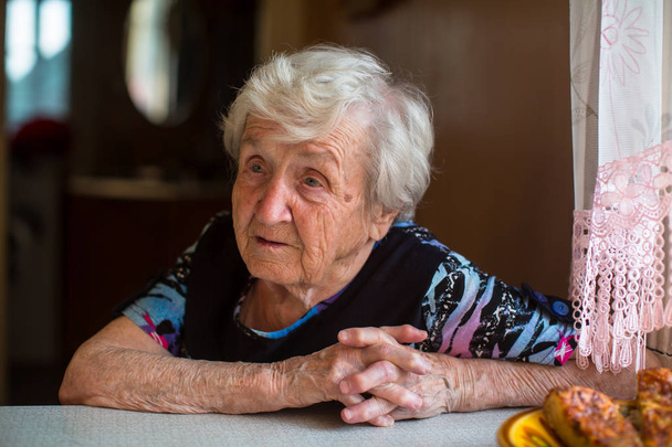 Ritratto di una donna anziana seduta al tavolo della cucina
. - Foto, immagini