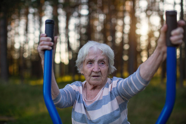 Mujer mayor haciendo ejercicio matutino en el patio de recreo deportivo de la calle
. - Foto, imagen