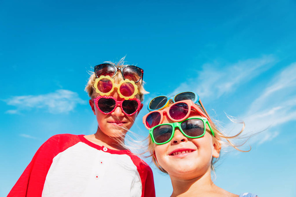 χαριτωμένο μικρό αγόρι και κορίτσι, δοκιμάστε σε γυαλιά ηλίου στην παραλία - Φωτογραφία, εικόνα
