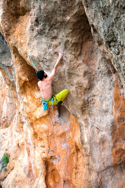 A man climbs the rock. Climbing in nature. Fitness outdoors. Active lifestyle. Extreme sports. The athlete trains on a natural relief. - Photo, Image